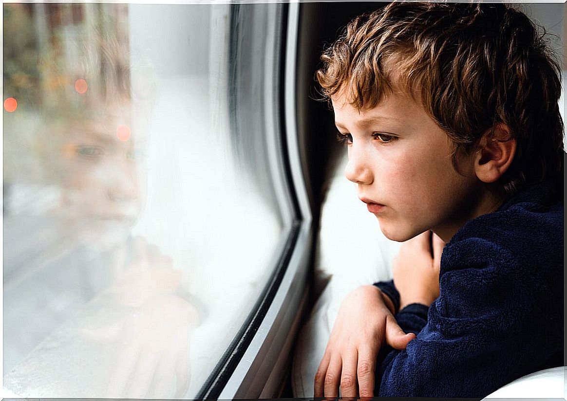 Sad child looking out the window suffering emotional isolation