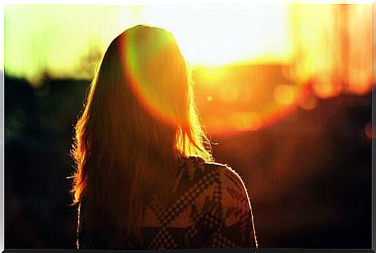 Girl with her back turned to sunrise thinking about facing her problems