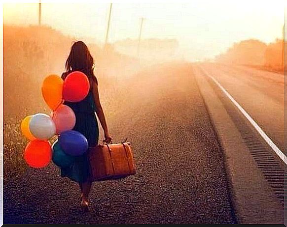 Woman walking with a suitcase and colorful balloons