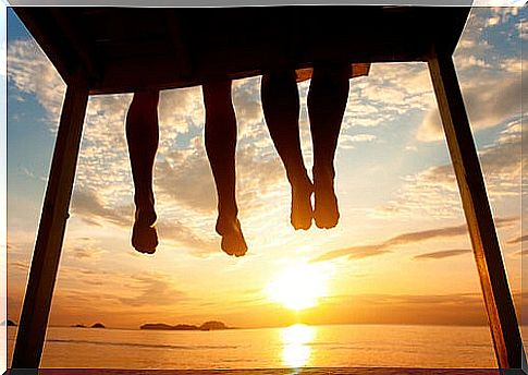 Legs of friends sitting watching the sunset