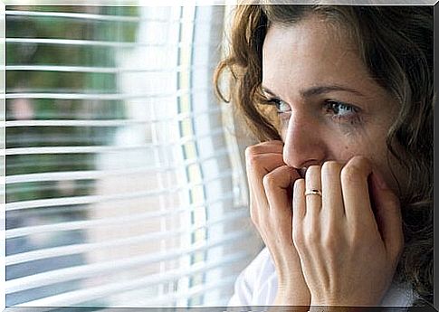 Woman with fear looking out of a window