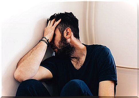 Man leaning on wall with hand on face suffering from partner abuse